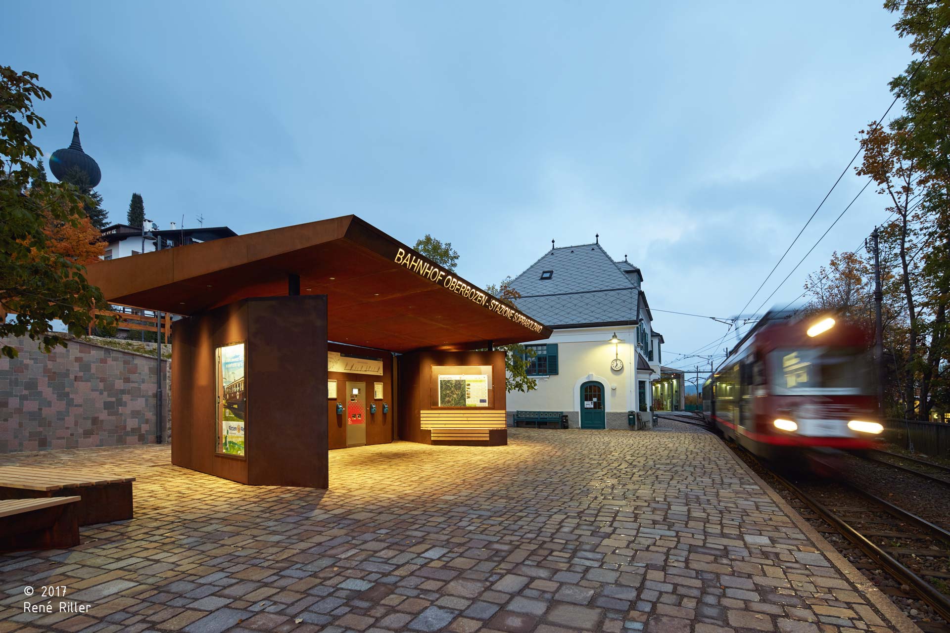 Ing.-Josef-Riehl Platz; Bahnhofsplatz; Südtirol; Stützmauer; Tradition von Renon; Porphyr; Trockenmauer; Bahnhof des Jahres 2018; monovolume architecture + design; Architektur Südtirol; moderne Architektur; monovolume Architekten